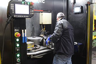 Image of welding operator checking fixturing in robotic MIG welding cell