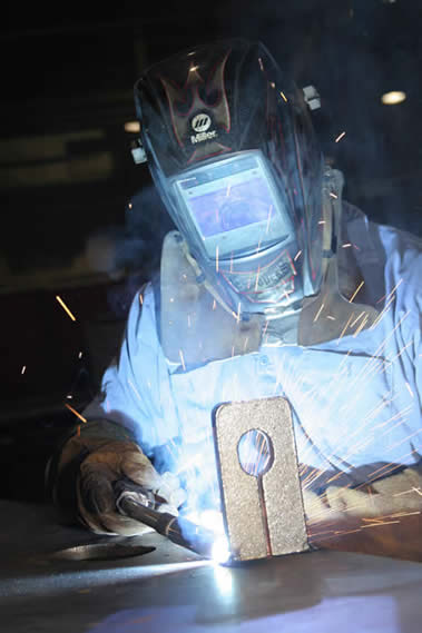 Image of a welder using a MIG gun in a shop setting