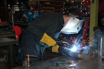 Image of welder leaning over to see the weld more closely