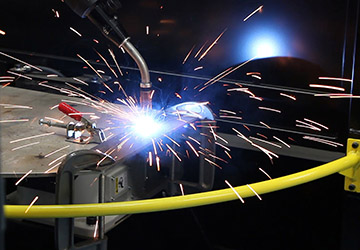 Image of a robotic welding MIG gun with sparks