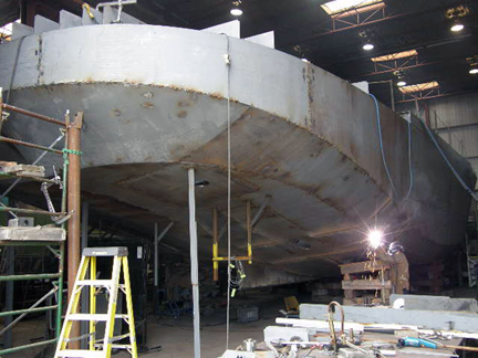 Image of a boat being manufactured and a welder at the base of the huge boat welding
